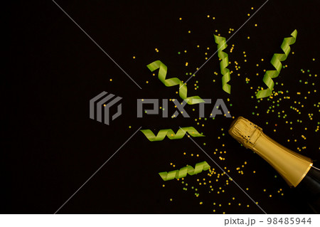 Festive party concept, Champagne bottle with green ribbon and confetti stars on back background Festive party concept, Champagne bottle with green ribbon and confetti stars on back background 98485944