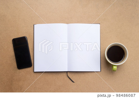 blank notebook,cup of coffee and smartphone on brown wood table blank notebook,cup of coffee and smartphone on brown wood table 98486087