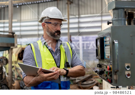 Industrial man engineer wear uniform and helmet using Tablet are checking system machine Industrial man engineer wear uniform and helmet using Tablet are checking system machine 98486521