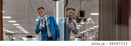 Happy bearded man standing at the entrance to the office Happy bearded man standing at the entrance to the office 98487235