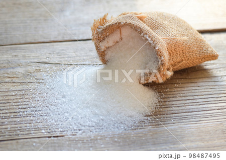 Sugar sack on wooden background, white sugar for food and sweets dessert candy heap of sweet sugar crystalline granulated 98487495