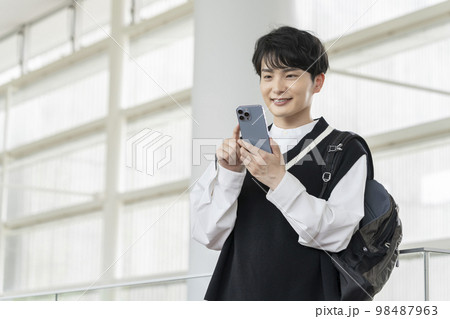 スマートフォンを持った笑顔の若い男性 98487963