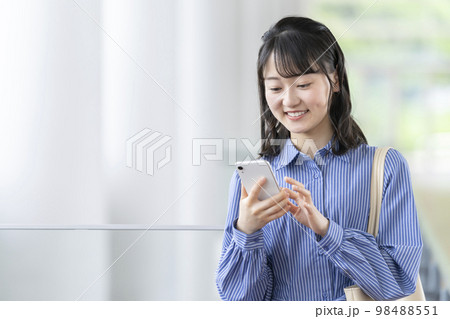 スマートフォンを操作する笑顔の若い女性 98488551