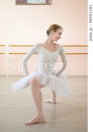 A very flexible ballerina in a tutu stands in a plie in a class with ballet machines. Hypermobility of joints and connective tissue dysplasia. A very flexible ballerina in a tutu stands in a plie in a class with ballet machines. Hypermobility of joints and connective tissue dysplasia. 98491281
