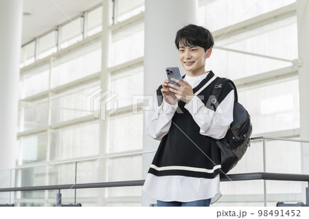 スマートフォンを持った笑顔の若い男性 スマートフォンを持った笑顔の若い男性 98491452