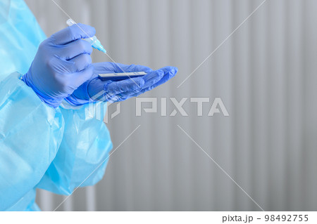 Doctor's hands performing antigen analisys of the fluid sample 98492755