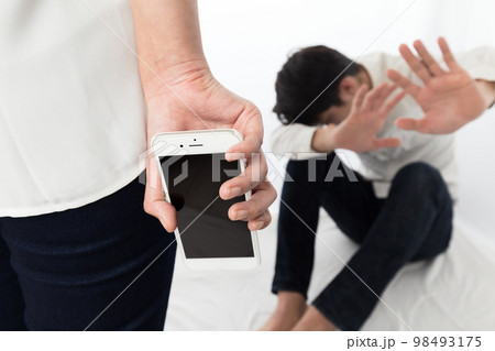 スマートフォンを持つ女性に怖がる男性. スマートフォンを持つ女性に怖がる男性. 98493175