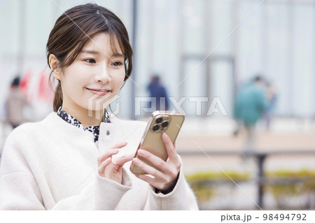 ショッピングモールの前でスマホを見る若い女性 98494792