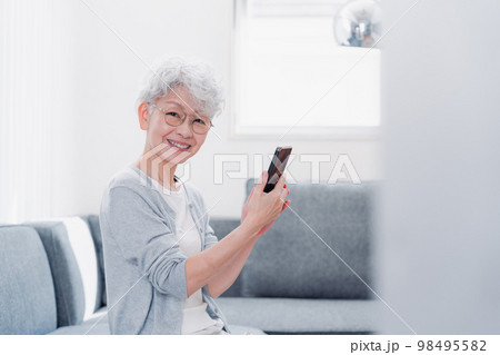 笑顔でスマホを操作するシニアの女性 笑顔でスマホを操作するシニアの女性 98495582