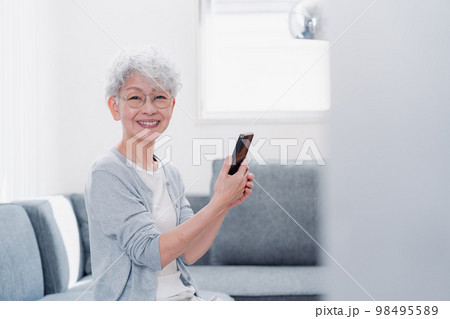 笑顔でスマホを操作するシニアの女性 笑顔でスマホを操作するシニアの女性 98495589