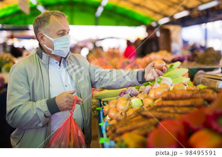 Middle aged man in mask buying onions Middle aged man in mask buying onions 98495591