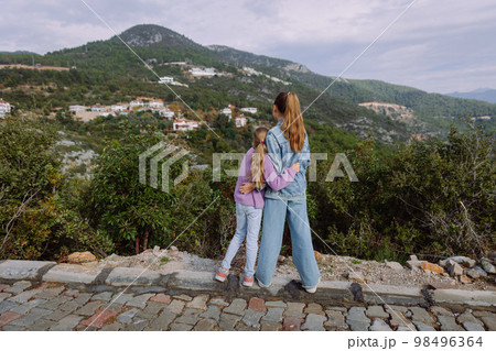 Two sisters hugging and looking at mountains on a cloudy day, back view 98496364