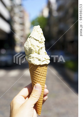 Ice cream in hand. Waffle cone with ice cream on the background of the street in the summer on a hot day. Street food, sweets, desserts concept. 98498153