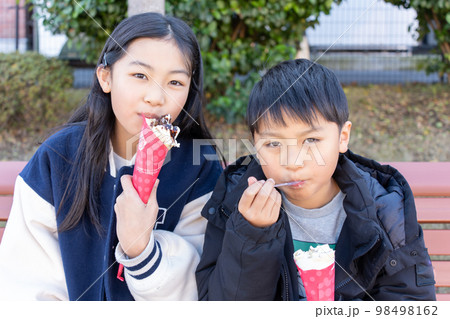 クレープを美味しそうに食べる小学生の男の子と女の子 98498162