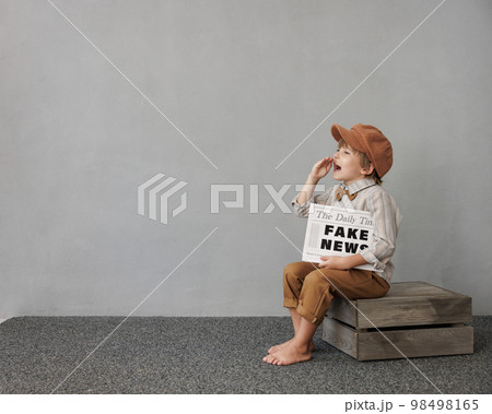 Newsboy shouting against grunge wall background. Boy selling fake news 98498165