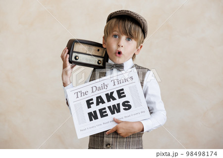 Newsboy shouting against grunge wall background. Boy selling fake news Newsboy shouting against grunge wall background. Boy selling fake news 98498174