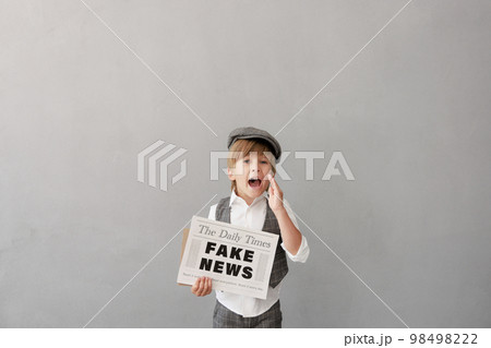 Newsboy shouting against grunge wall background. Boy selling fake news 98498222