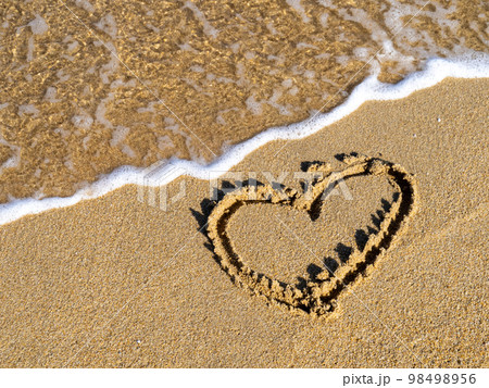 綺麗な海の波打ち際に描かれたハート。 98498956