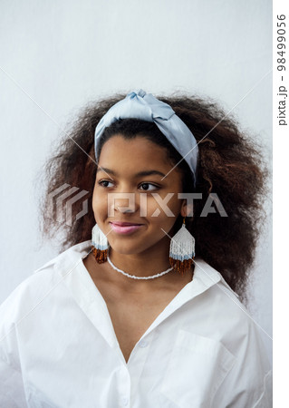 Portrait of young african woman with headscarf and ethnic jewelry. African beautiful brunette curly haired young model 98499056