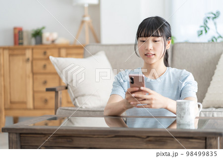 リビングでスマホを見る女子高生 リビングでスマホを見る女子高生 98499835