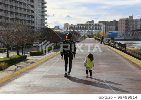 お母さんとこどもが散歩する後ろ姿、よちよち歩きの子供を見守るお母さんの姿に愛を感じる 98499914