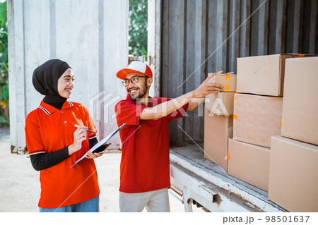 male and female employees manage products packed in logistics trucks 98501637