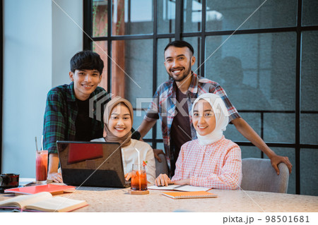 four young Asian people smiling in a cafe four young Asian people smiling in a cafe 98501681
