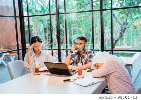 group of sad students using a laptop while working together 98501713