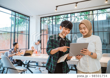 Asian student couple using a tablet with cafe as background Asian student couple using a tablet with cafe as background 98501754