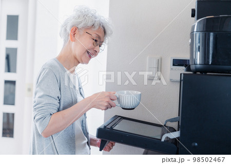 電子レンジでカップを温めるシニアの女性 98502467
