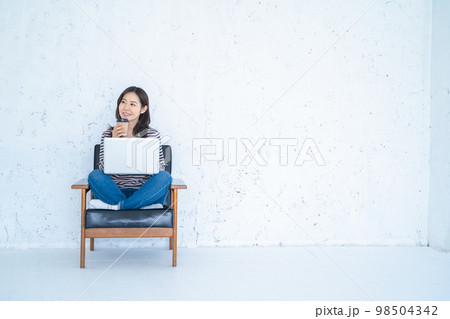 白い明るいリビングでリモートワークをする女性 98504342