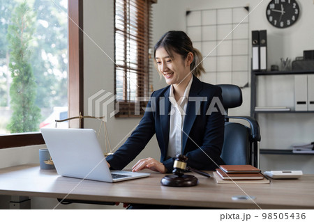 Attractive young lawyer in office Business woman and lawyers discussing contract papers with brass scale on wooden desk in office. Law, legal services, advice, Justice and real estate concept 98505436