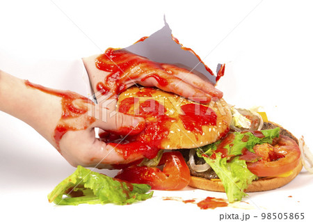 A hamburger is holding a ketchup-smeared hand on a white background.Creative hamburger. 98505865