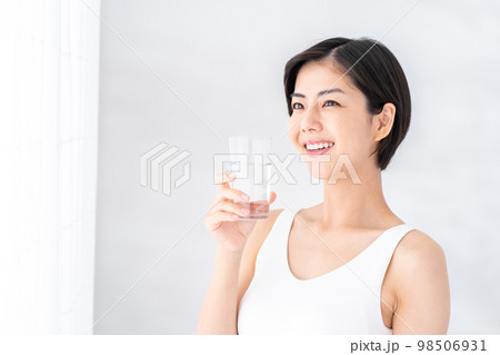 窓際で水を飲む女性。 98506931
