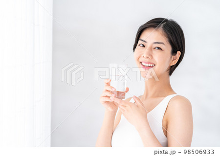 窓際で水を飲む女性。 98506933