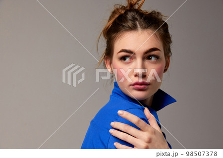 Fashionable stylish emotional woman wearing blue shirt posing over gray background. Model with vivid facial expression. Concept of fashion, style, youth, beauty 98507378