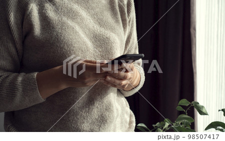 Closeup image of a beautiful young asian woman holding and using mobile phone 98507417