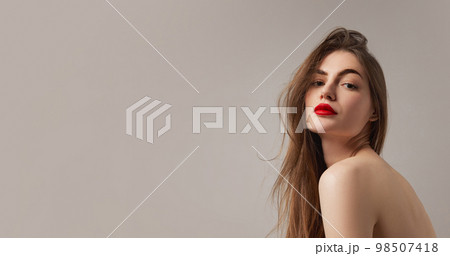 Portrait of tender sensual young woman wearing nude color underwear isolated over grey background. Girl with red lipstick. Accent makeup 98507418