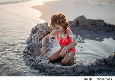 Little girl playing on the beach, digging hole in sand. Little girl playing on the beach, digging hole in sand. 98507583