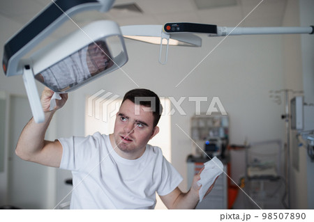 Young man with down syndome working in hospital as helper, cleaner. Concpet of integration people with disability into society. 98507890