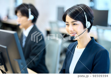 オフィスでヘッドセットをつけて対応するオペレーターの女性 98509394