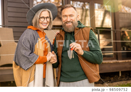 Happy man and woman standing near their new house and smiling 98509752
