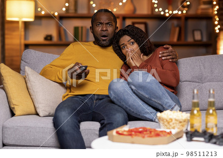 Frightend black couple watching horror movie at home Frightend black couple watching horror movie at home 98511213