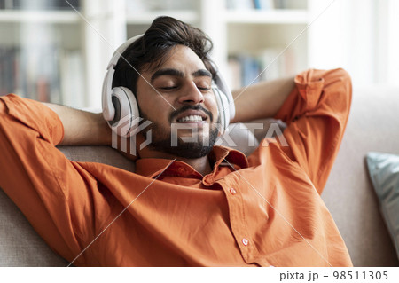 Happy middle eastern man resting at home, listening to music 98511305