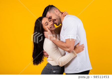 Happy attractive young middle eastern woman and man in casual hugging, kiss, enjoy love 98511453