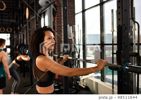 Athletic african american woman in crossfit gym close up smiling leaning on a barbell. Athletic african american woman in crossfit gym close up smiling leaning on a barbell. 98511644