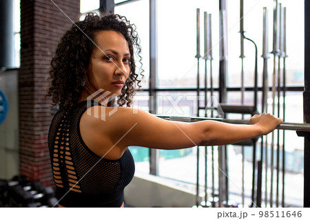 Athletic african american woman in crossfit gym close up smiling leaning on a barbell. 98511646