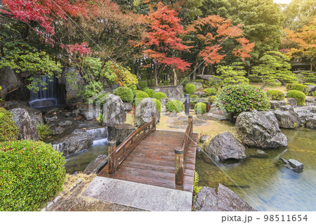 [九州・福岡] 福岡県立大濠公園日本庭園の布落ちの滝を渡る木製橋の秋の風景。 98511654