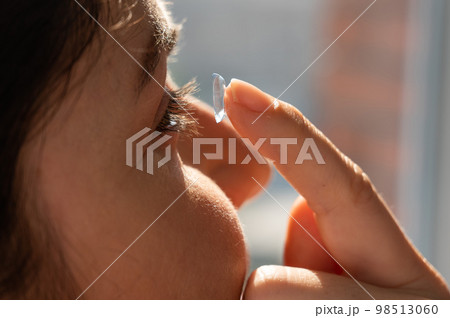 Close-up portrait caucasian woman putting on a contact lens. Close-up portrait caucasian woman putting on a contact lens. 98513060