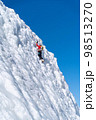 A climber in a red suit climbs an icy white mountain 98513270